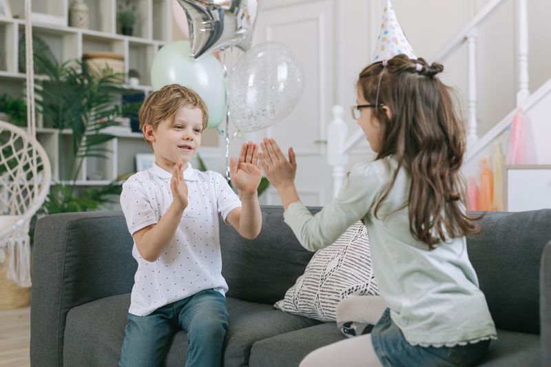 Children joyfully playing clapping games at a birthday party indoors.
