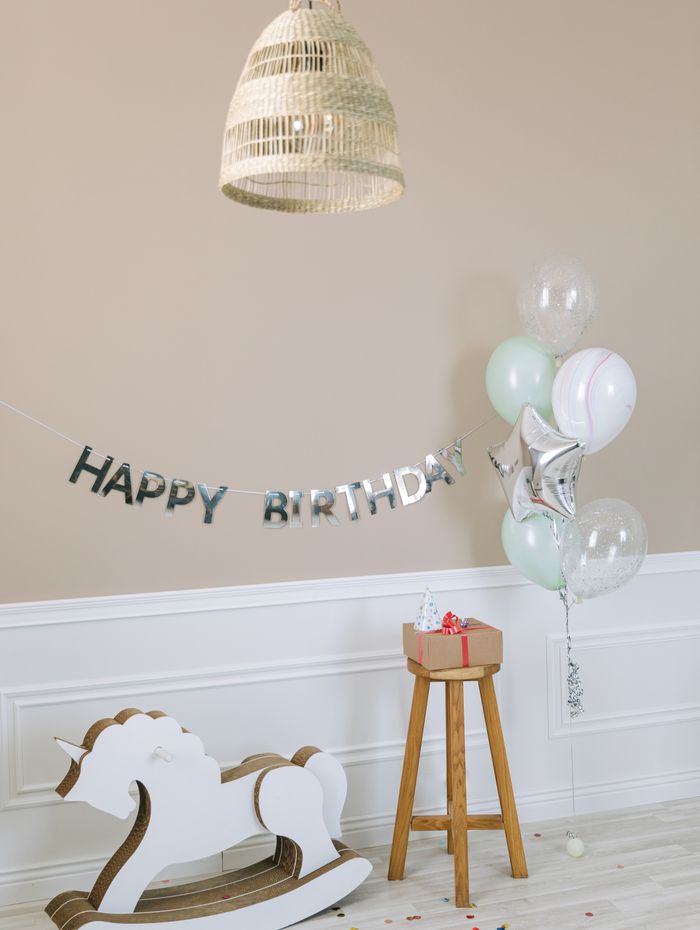 Kids birthday setup with balloons, banner and rocking horse