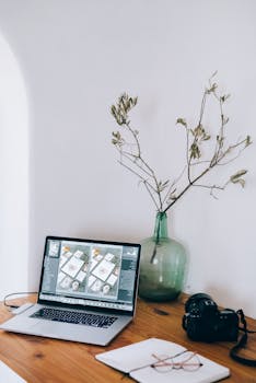A neat wooden desk with a DSLR, laptop, and decorative plant interior setup.