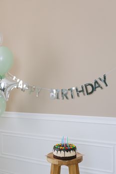 Elegant birthday setup with cake and balloons indoors.