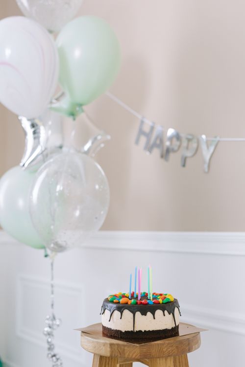 Free A colorful birthday cake with balloons in a festive indoor celebration setting. Stock Photo