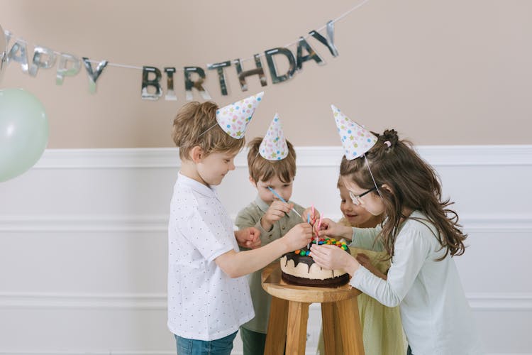 Children Putting Candles On A Cake