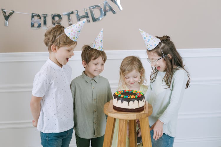 Children Looking At A Cake On A Bar Stool