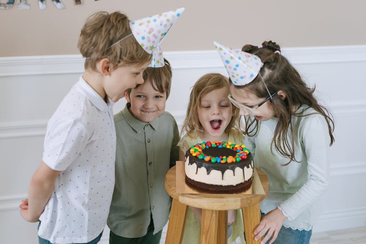 
Children Looking At A Cake On A Bar Stool