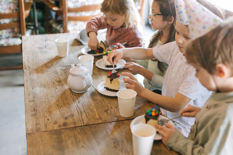 Group Of Kids Eating Cake On The Table