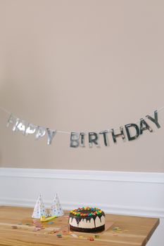 A vibrant birthday setup featuring a decorated cake and party hats on a wooden table.