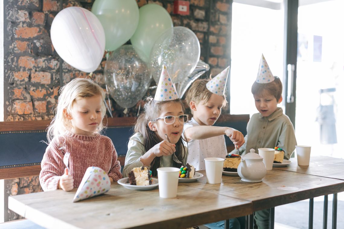 Children enjoying a birthday celebration with cake, balloons, and party decorations