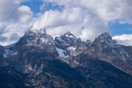 A breathtaking view of the snow-dusted Grand Teton peaks in Wyoming set against a dramatic cloudy sky.
