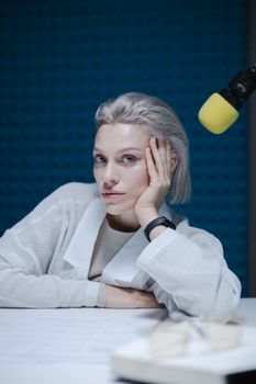Portrait of a woman recording a podcast in a studio with microphone.