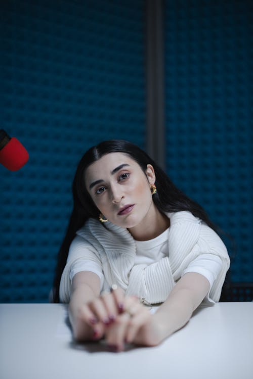 woman sitting near the red mic while seriously looking at the camera
