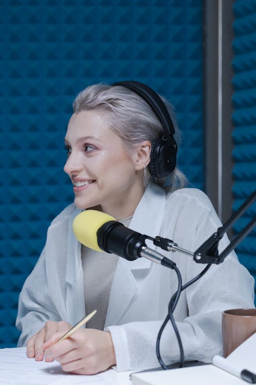 Woman in White Long Sleeve Shirt Wearing Black Headphones