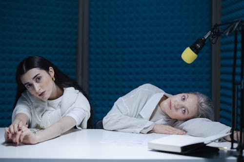 Woman in White Shirt Sitting Beside Woman in White Long Sleeve Shirt