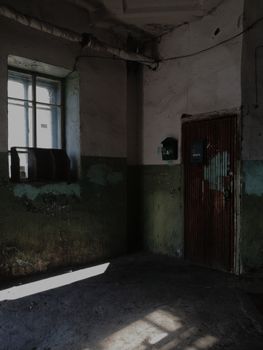 Atmospheric shot of an abandoned interior with peeling paint and dim light filtering through a window.