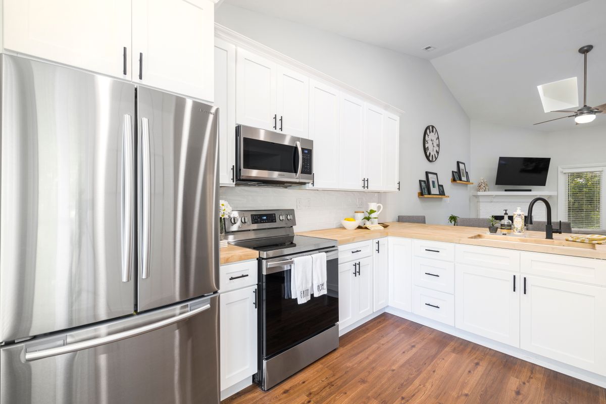 Bright modern kitchen with white cabinets and wood countertop