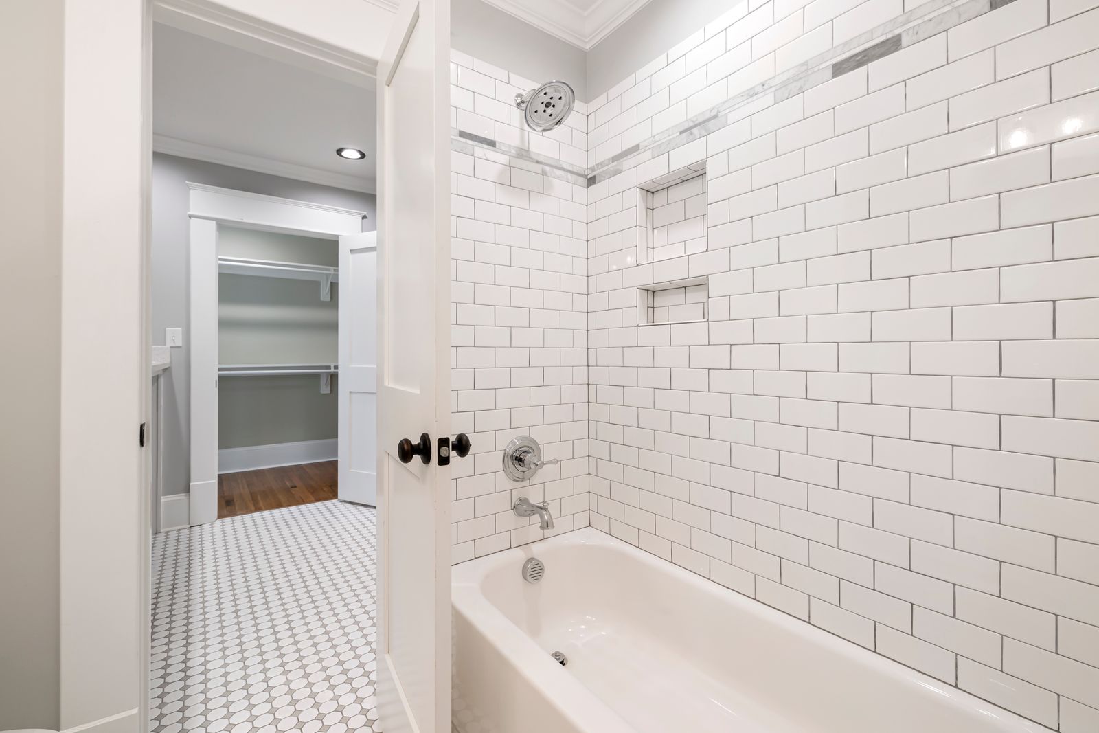 Bathroom with a tiled bathtub and adjacent closet opening, illustrating adjoining-space possibilities.