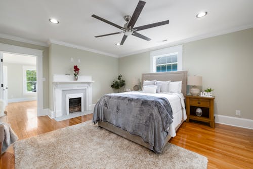 A Cozy Bed with Ceiling Fan on Top