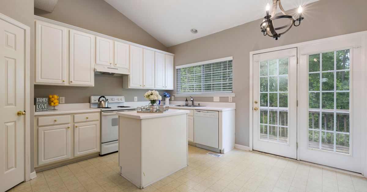 A clean and bright kitchen featuring white cabinets, a center island, and natural light.