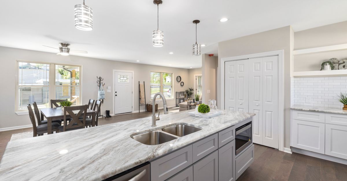 Bright modern kitchen with marble countertop and dining area.