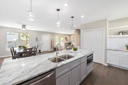 Bright modern kitchen with marble countertop and dining area.