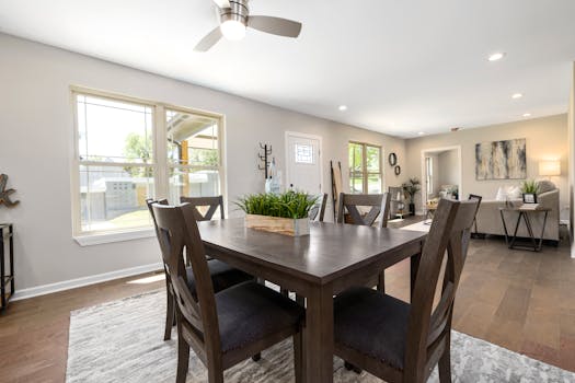 Spacious modern dining room featuring a wooden table and large windows allowing natural light.
