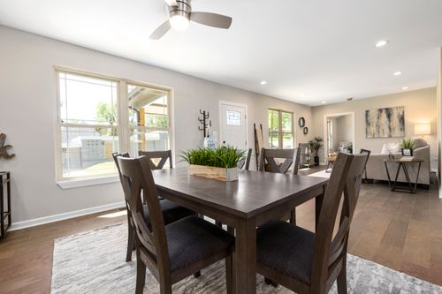 Free Spacious modern dining room featuring a wooden table and large windows allowing natural light. Stock Photo