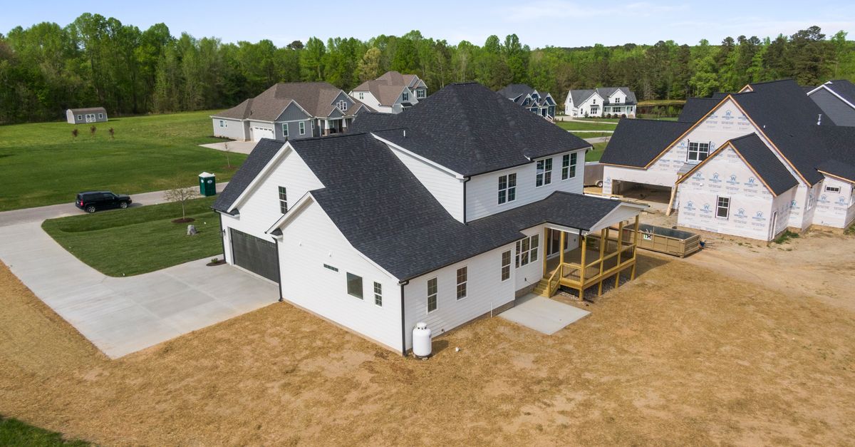 Aerial view of newly constructed homes in a suburban neighborhood in Youngsville, NC, surrounded by greenery.