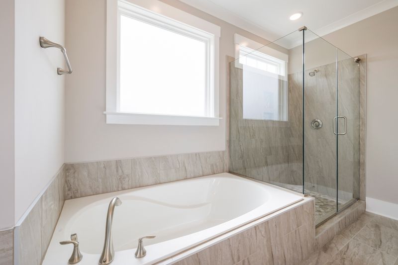 Luxurious bathroom interior featuring a white bathtub and glass-enclosed shower with marble accents.