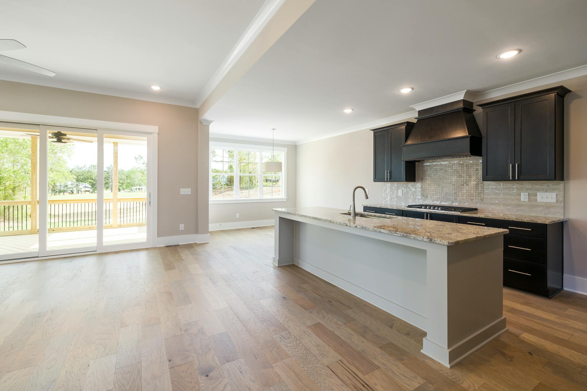 Spacious modern kitchen interior with island, light wood flooring, and natural light.