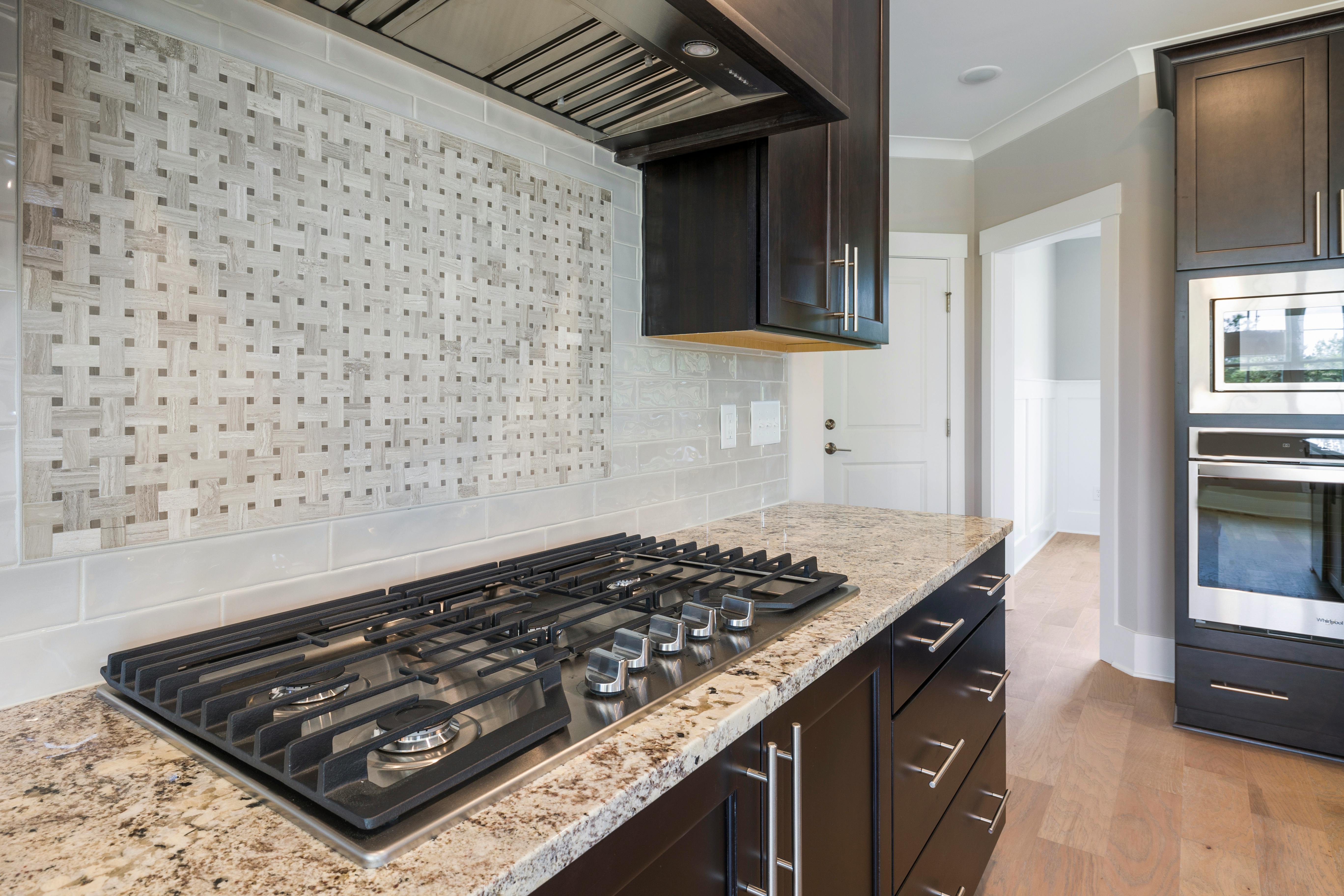 Contemporary kitchen featuring a sleek granite countertop, integrated oven, and stylish backsplash.