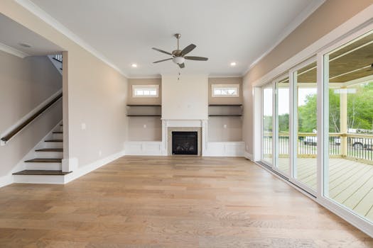 A contemporary living room featuring wooden floors, fireplace, and large glass sliding doors.
