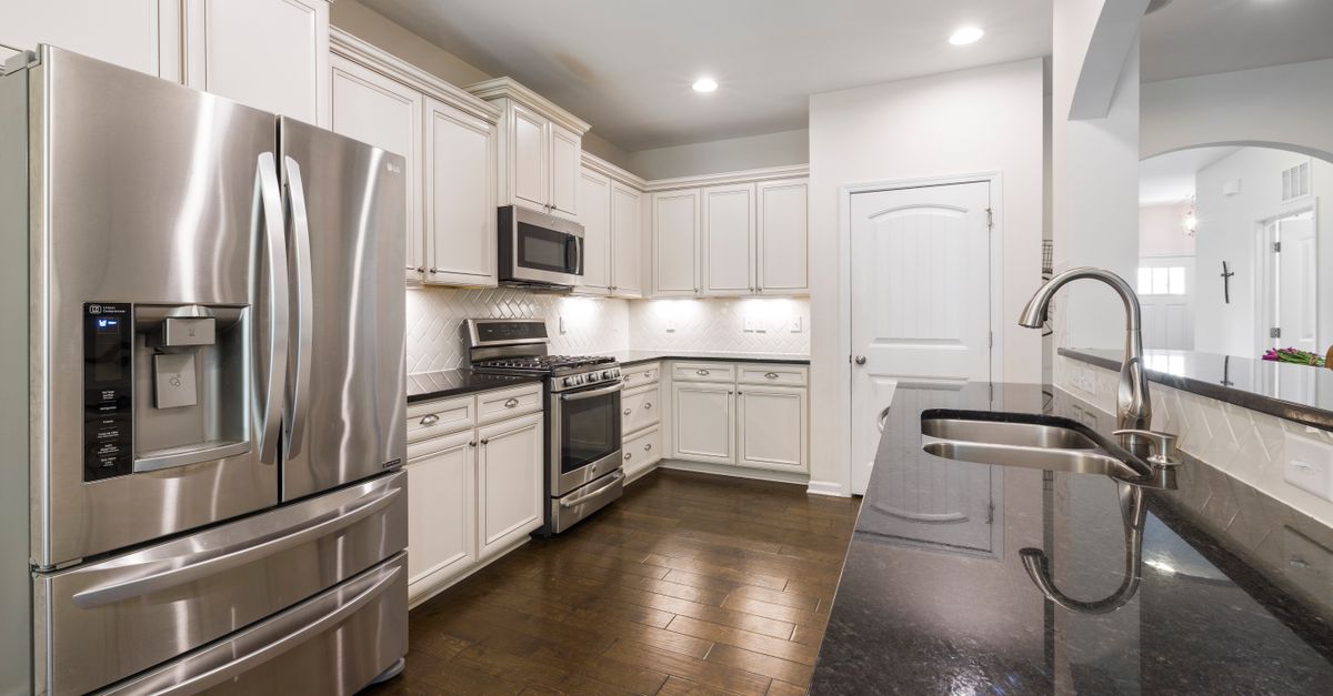 Bright modern kitchen with stainless steel appliances, granite countertops, and wooden flooring.
