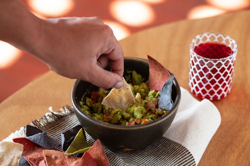 Free A Person Dipping Chip on Guacamole Stock Photo