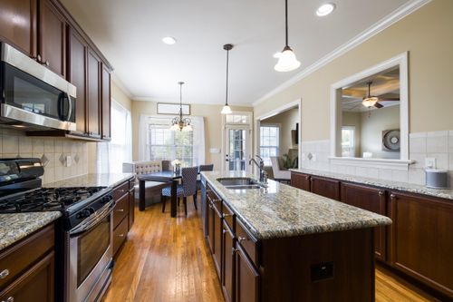 Free Spacious modern kitchen featuring wooden cabinets, a central island, and elegant lighting. Stock Photo