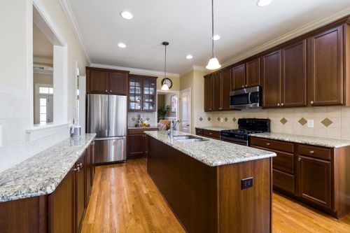 Free Spacious modern kitchen featuring granite countertops and wooden cabinetry. Stock Photo