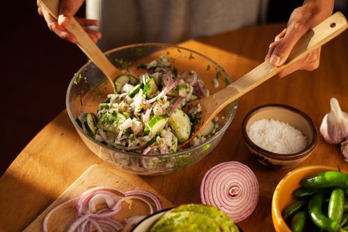Free Close-up of fresh Mexican salad being prepared with zucchini, onion, and herbs in a cozy kitchen setting. Stock Photo
