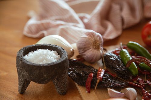 Free A collection of Mexican culinary ingredients including peppers, garlic, and salt on a kitchen table. Stock Photo