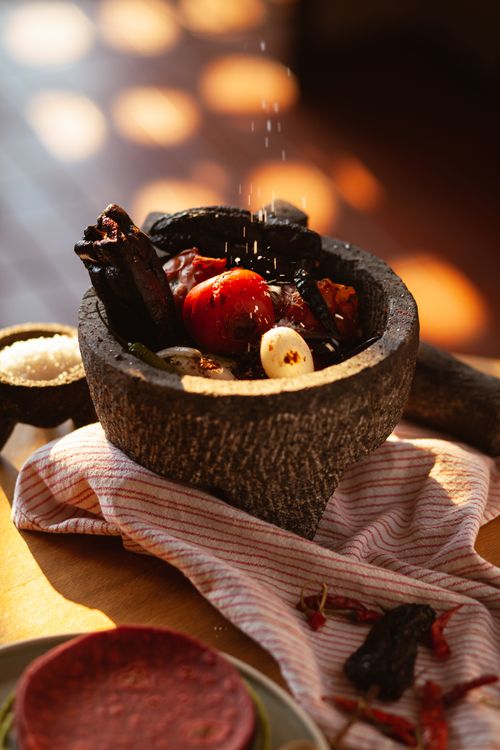Free Close-up of Mexican molcajete with tomatoes, garlic, and seasoning in sunlight. Stock Photo