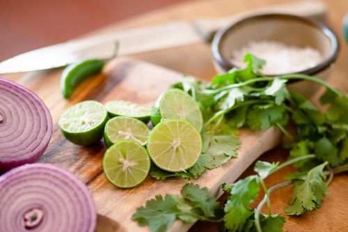 Free Citrus, coriander, and red onion on a cutting board for food prep. Stock Photo