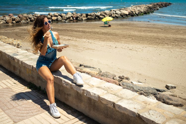 Woman Eating At The Beach