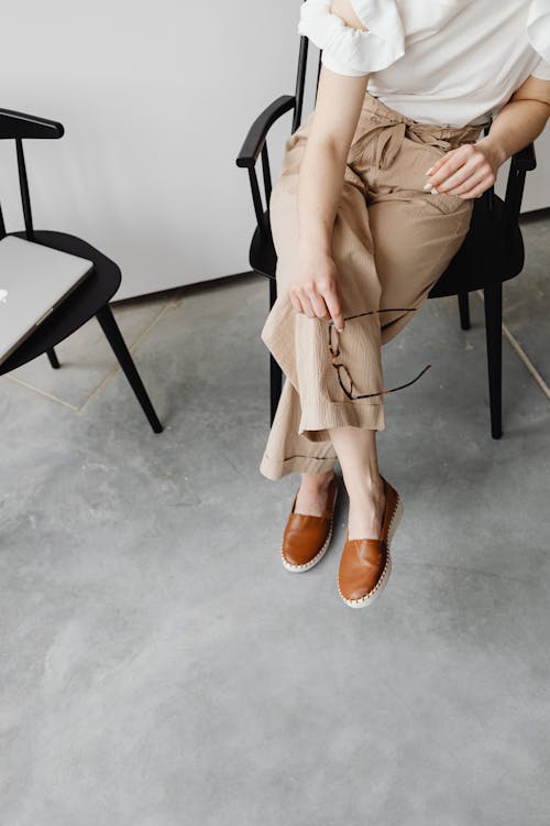 Woman in Brown Pants Sitting on a Chair