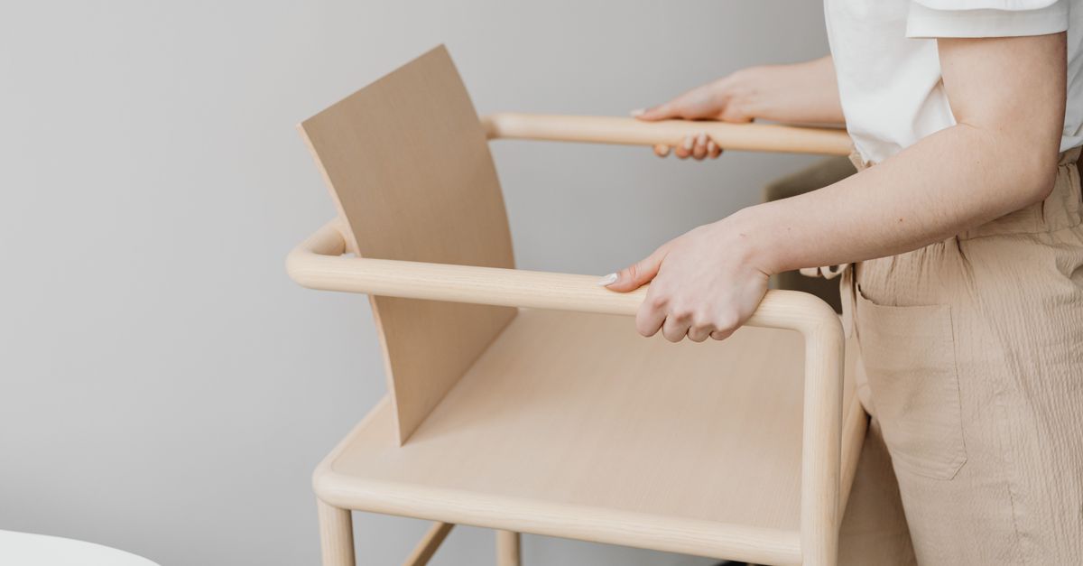 A woman holding a minimalist wooden chair, showcasing Scandinavian design
