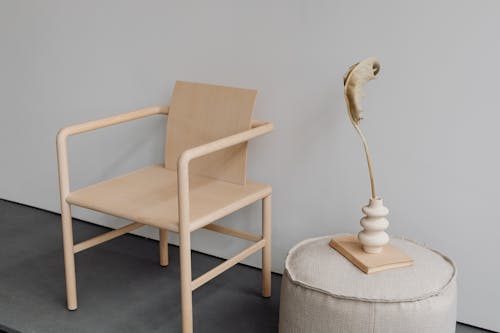 Free A minimalist wooden chair alongside a modern vase and pouf, showcasing elegant design. Stock Photo