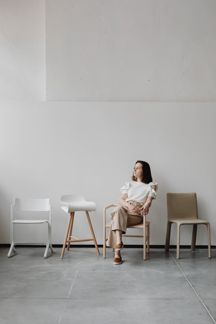 Woman Sitting In One Of Mismatched Chairs