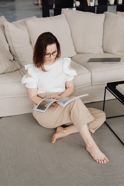 A Woman Reading a Magazine while Sitting on the Floor