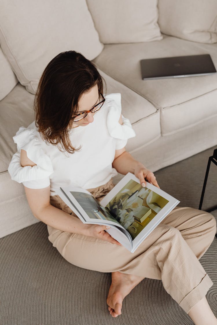 Woman Sitting On Floor And Reading Catalogue