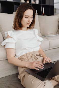 A woman sits on the floor at home, working remotely on a laptop, embodying the digital nomad lifestyle.