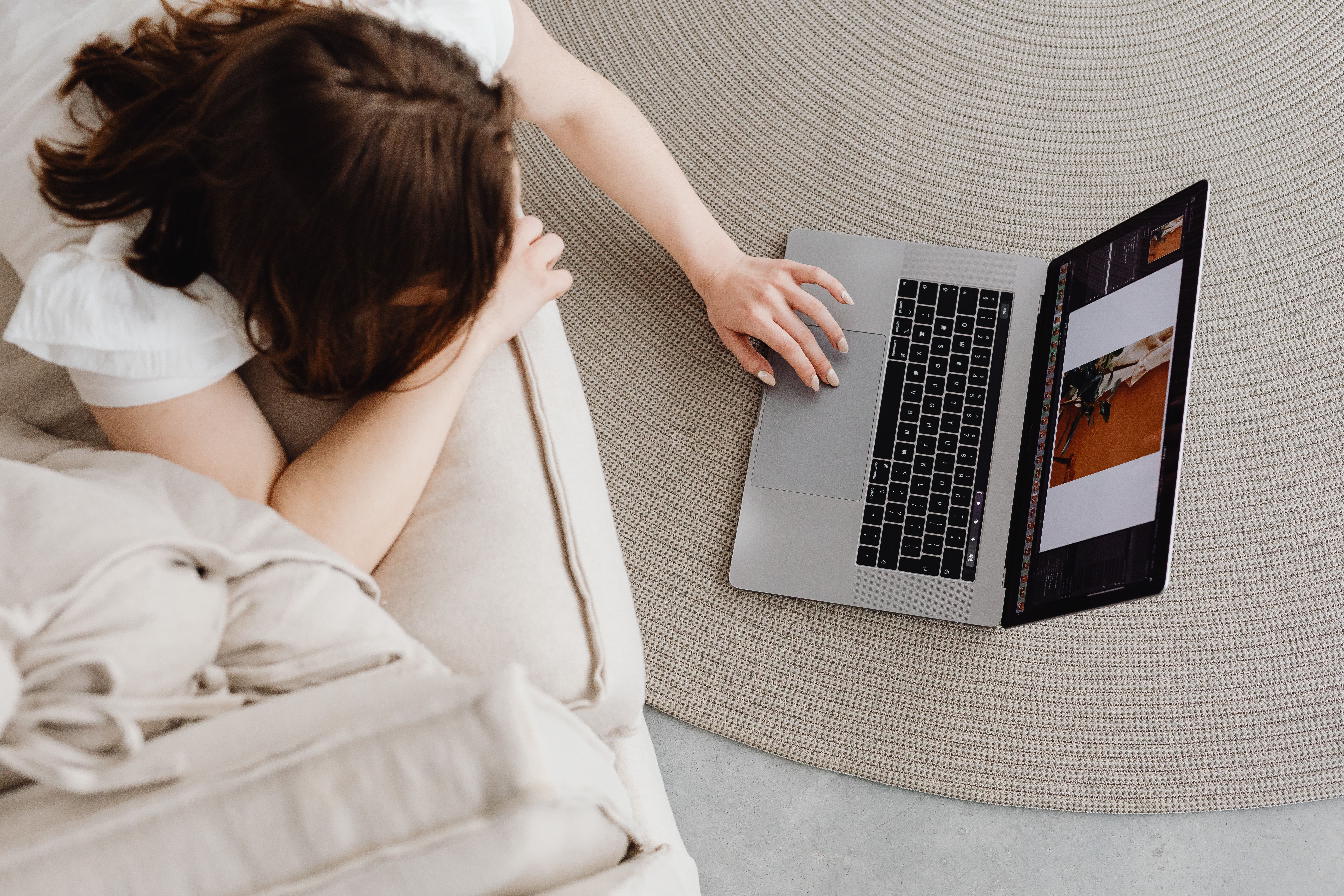 Overhead view of a woman working remotely on a laptop at home, illustrating a modern lifestyle.