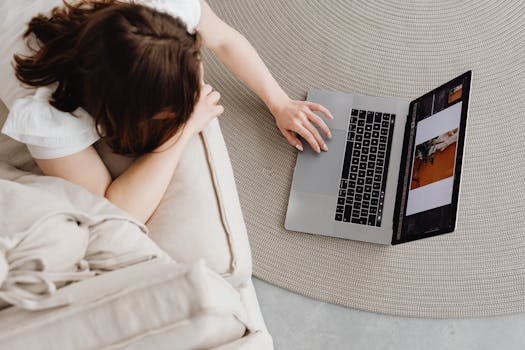 Overhead view of a woman working remotely on a laptop at home, illustrating a modern lifestyle.