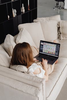 A comfortable home office setup showing a woman working on her laptop from a cozy couch.