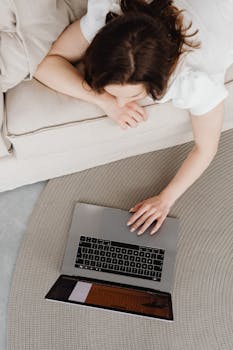 A woman lying on the floor working on a laptop, embodying a digital nomad lifestyle.